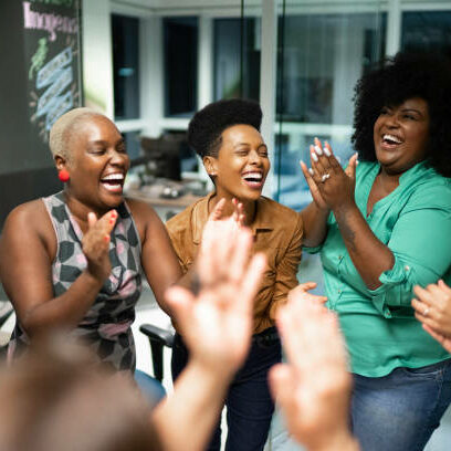Group of women laughing while clapping.